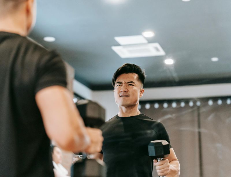 A strong man holding heavy dumbbells in a moody gym